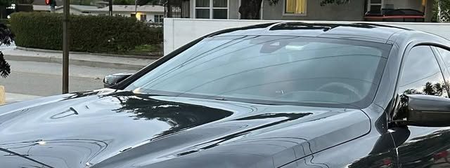Black BMW M8 after a detail, its hood reflecting the trees and sky